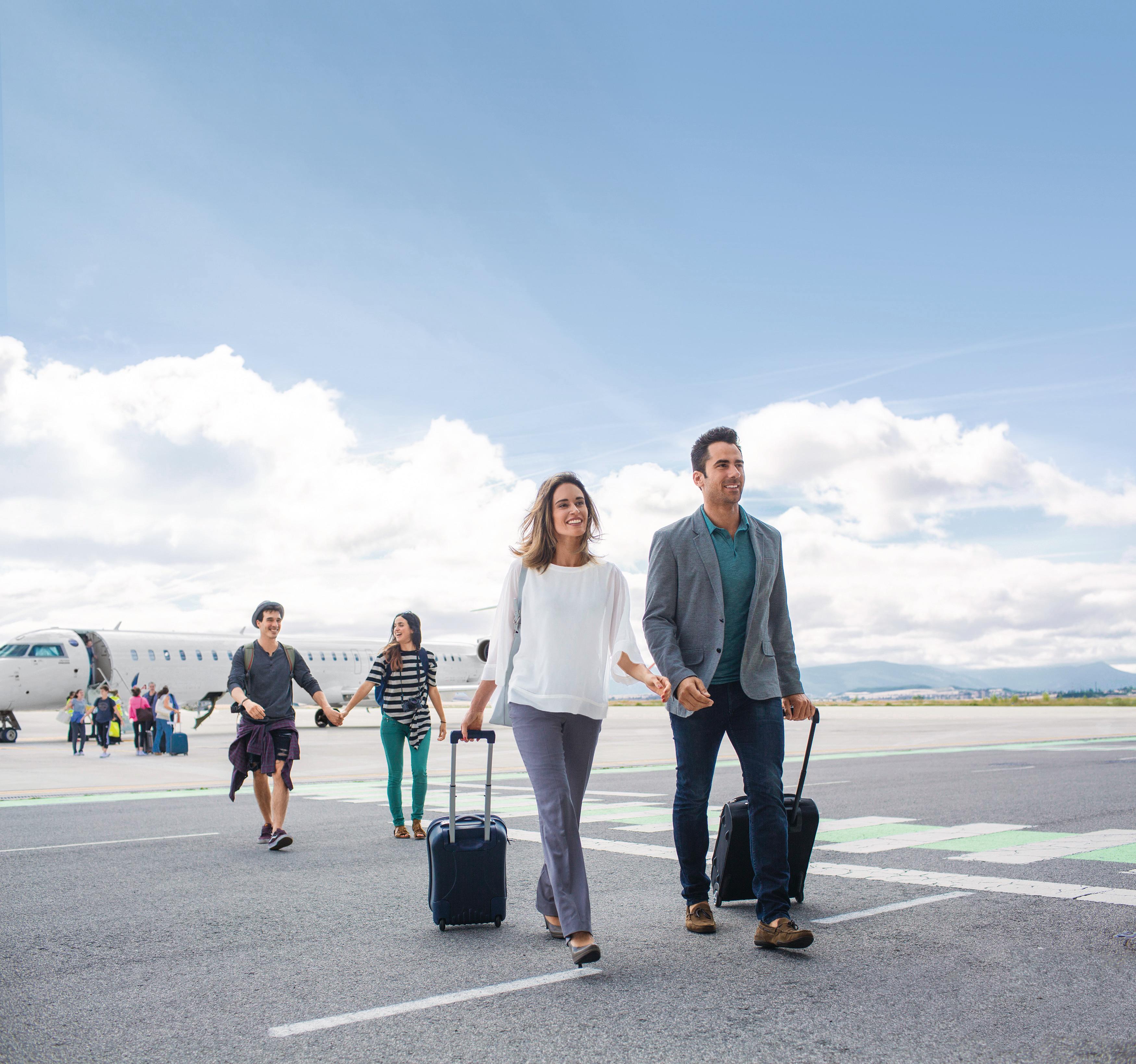 Eine Familie geht auf dem Rollfeld eines Flughafens. Im Hintergrund kann man ein Flugzeug sehen.