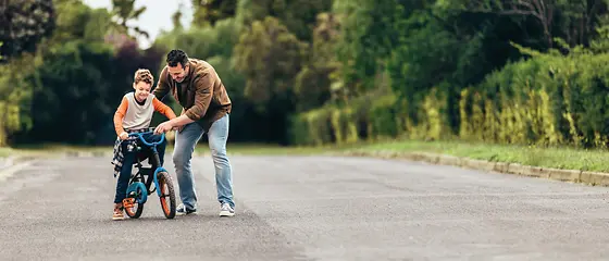 Vater hilft seinem Buben mit dem Velo